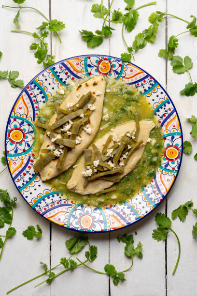 Drowned tlacoyos in green sauce with nopales on white background. Mexican food Drowned tlacoyos in green sauce with nopales on white background. Traditional mexican food tomatillo photos stock pictures, royalty-free photos & images