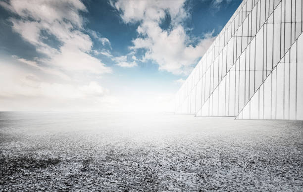 istock Rough asphalt pavement and white triangular building wall under the blue sky, car advertisement synthetic creative background. 1318949894
