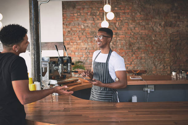 istock Shot of a young man using a digital tablet while serving a customer in a cafe 1318951851