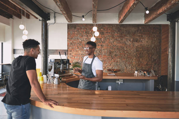 istock Shot of a young man using a digital tablet while serving a customer in a cafe 1318951852