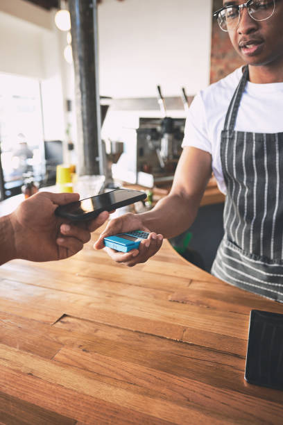 istock Shot of a man using a smartphone to make a payment in a cafe 1318951973