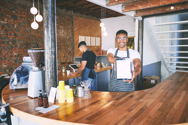 istock Shot of a young man showing a digital tablet with a blank screen while working in a cafe 1318953579