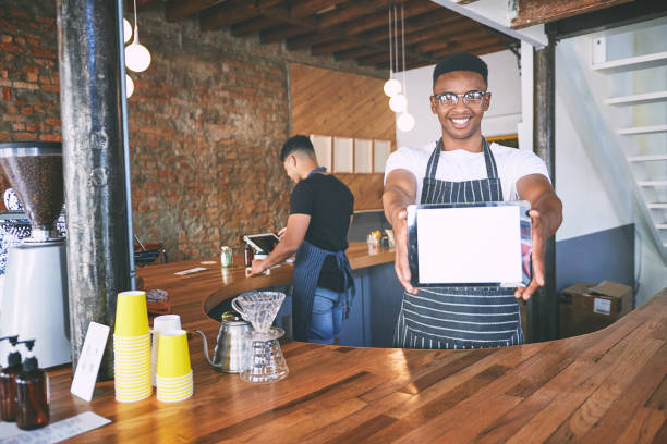 istock Shot of a young man showing a digital tablet with a blank screen while working in a cafe 1318953580