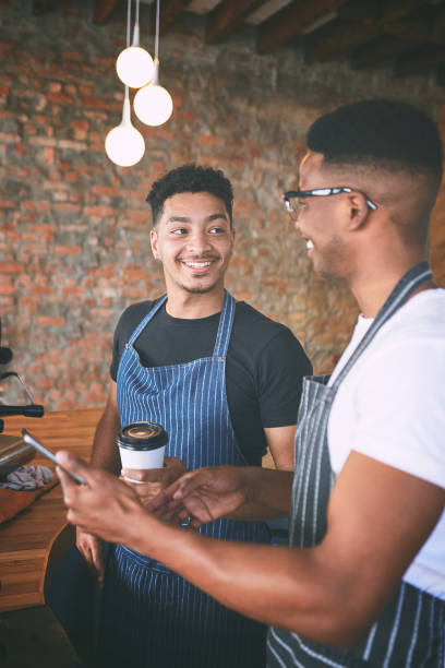 istock Shot of two young men using a digital tablet while making coffee at a cafe 1318954454