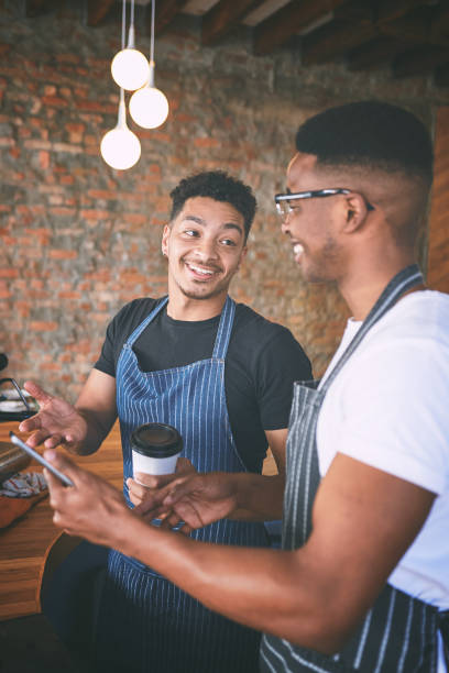 istock Shot of two young men using a digital tablet while making coffee at a cafe 1318954455