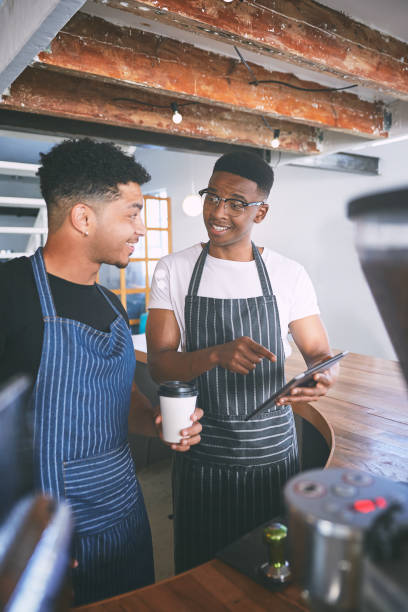 istock Shot of two young men using a digital tablet while making coffee at a cafe 1318954474