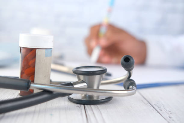 istock stethoscope, White sheet paper and pills on clinic table . 1318958437