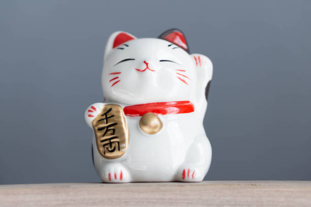 istock Maneki neko lucky cat show text on hand meaning rich on wood table background, select focus 1318958558