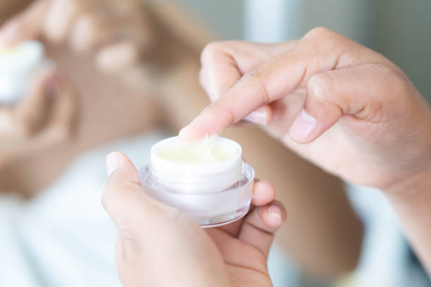 istock Close up woman hand applying cream or moisturizer from box for face beauty, selective focus 1318958606