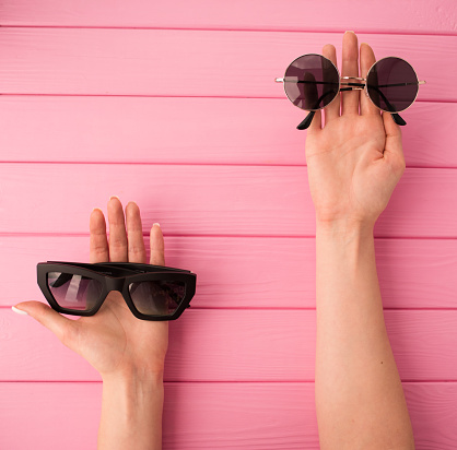 Summer abstract background mockup template free copy space for text pattern sample top view above on pink wooden board. blank empty area for inscription woman hands hold Couple sunglasses fashionable