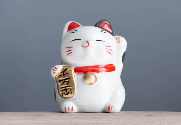 istock Maneki neko lucky cat show text on hand meaning rich on wood table background, select focus 1318963470
