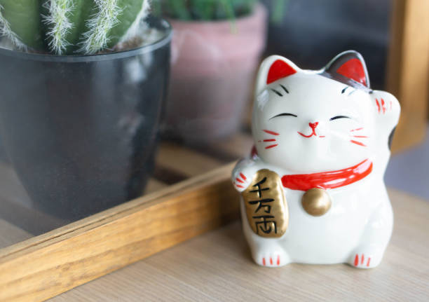 istock Maneki neko lucky cat show text on hand meaning rich on wood table background, select focus 1318964169