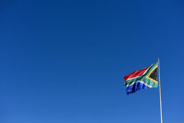 South African flag seen waving in the wind South African flag on flagpole against clear blue skyline south africa flag stock pictures, royalty-free photos & images