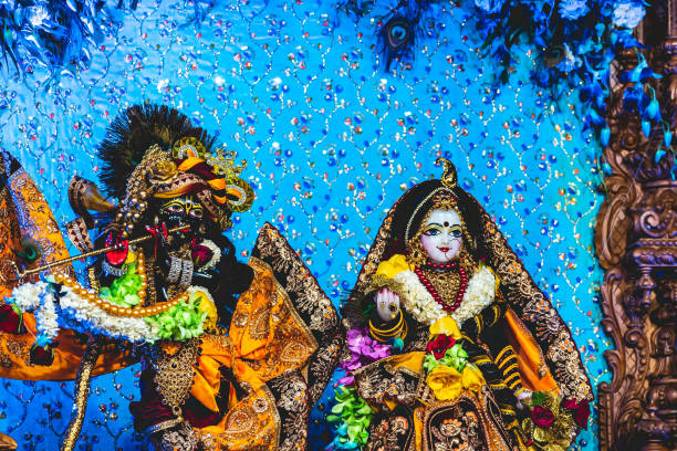 Decorated idol of Hindi god Krishna and Radha on Janmashtami festival. Close up of vibrant and beautiful marble and black stone statue of goddess Radha and lord Krishna decorated with colourful flowers, clothes and precious jewellery at the Indian temple. radha krishna stock pictures, royalty-free photos & images