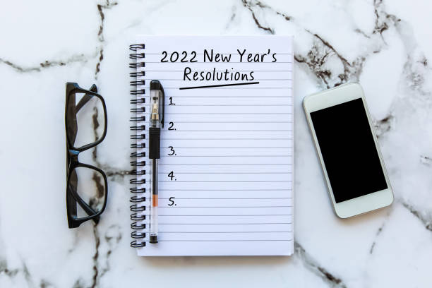 istock New year Concept - 2022 number and text on notepad. Smartphone, pen and eyeglass background. 1318969058