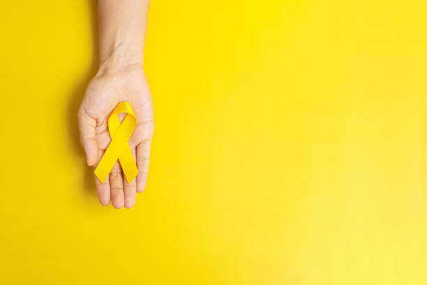 lazo amarillo en fondo amarillo para apoyar a las personas que viven y enferman. día de prevención del suicidio, concepto del mes del cáncer de sarcoma y del cáncer infantil - preventive fotografías e imágenes de stock