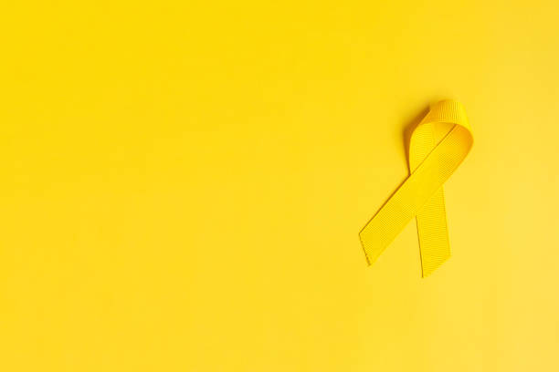 Yellow Ribbon on yellow background for supporting people living and illness. July Sarcoma cancer, Suicide prevention day, Childhood Cancer Awareness month concept Yellow Ribbon on yellow background for supporting people living and illness. July Sarcoma cancer, Suicide prevention day, Childhood Cancer Awareness month concept suicide photos stock pictures, royalty-free photos & images