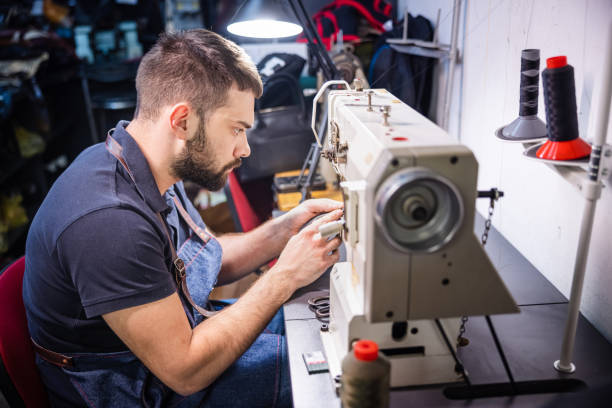 istock Man in crafts repair shop sawing shoulder strap 1318972674