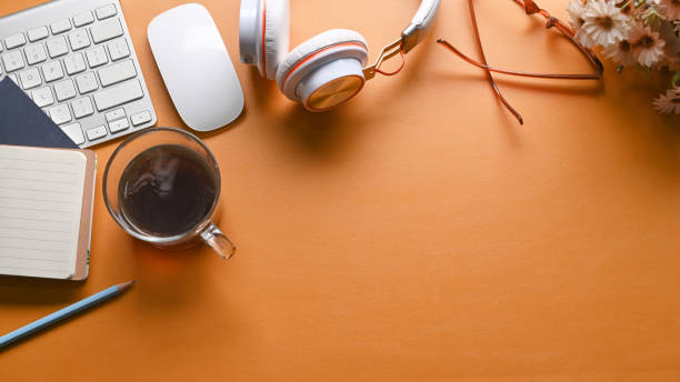 istock Top view stylish workspace with headphone, notebook, houseplant and coffee cup on yellow leather. 1318973435