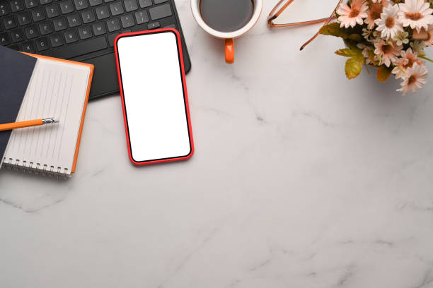 istock Mock up smart phone, laptop, notebook and coffee cup on marble table. 1318973915