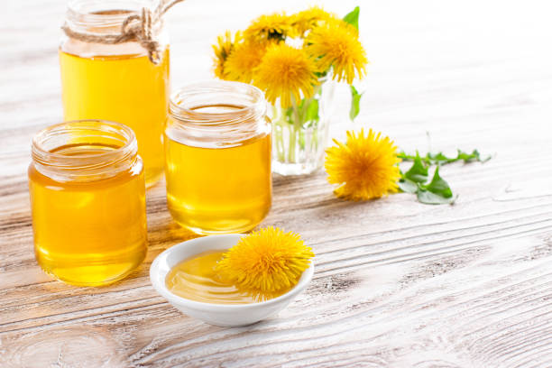 istock Dandelion honey in a jar and fresh flowers on white table. Copy space 1318975900