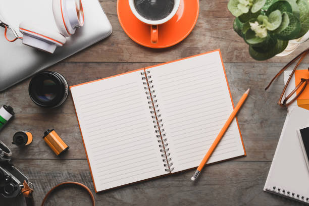 istock Top view of empty notebook, camera, coffee cup and headphone on wooden desk. 1318979301