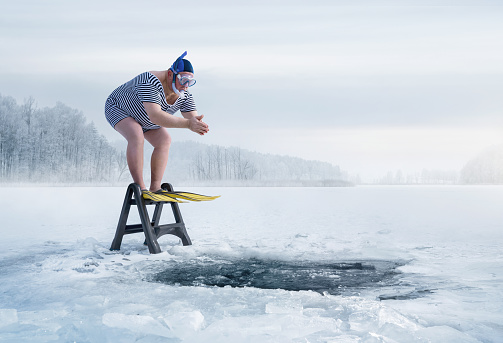 Fuunny overweight, retro swimmer about to jump into the ice hole in the lake, with copy space