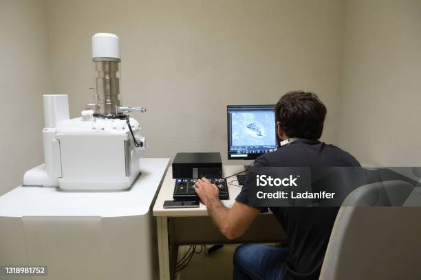 Young Man Scientist Working With Scanning Electron Microscope Laboratory Technician Observing Samples With A Sem Stock Photo - Download Image Now