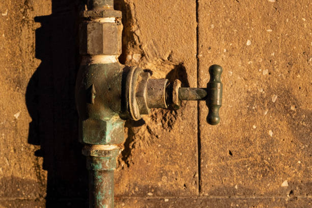 rubinetto e pipa arrugginiti vecchio su un muro al sole del pomeriggio - water pipe rusty dirty equipment foto e immagini stock
