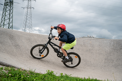 Young boy riding his bmx bike on a pumptrack.