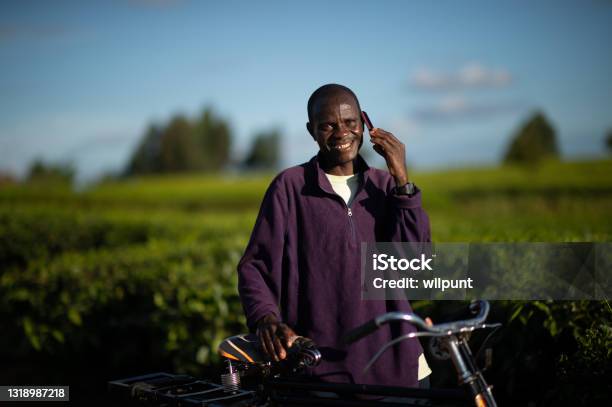 Happy Man With A Bicycle Looking At Camera Talking On A Mobile Phone In A Rural Setting Stock Photo - Download Image Now