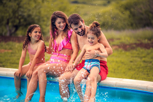 istock Happy family sitting by the swimming pool. 1318987724