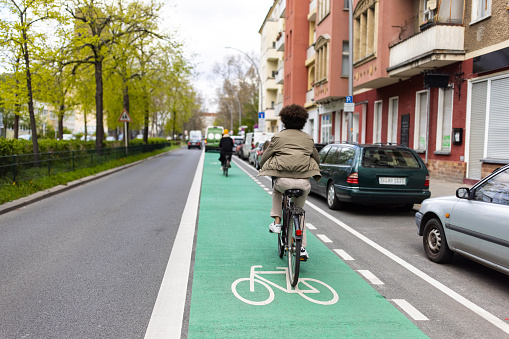 Rear view of a man driving his cycle in a dedicated bicycle lane in city. Man commuting in the city using bicycle.