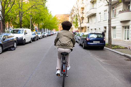 Rear view of a man riding bicycle in urban city. Male in commuting on cycle in the city.