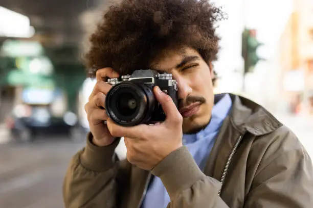 Close-up of a man clicking photos with digital camera while exploring  a foreign city. Man taking pictures touring while the city