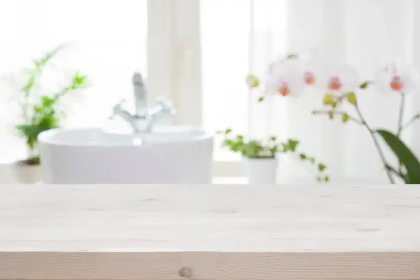 Photo of Wooden tabletop for product display on blur bathroom interior background