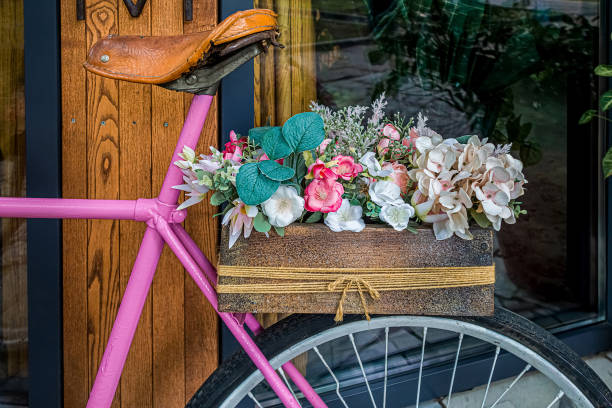 Summer decoration with artificial flowers in pot standing on old-fashioned pink bicycle.