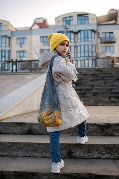 preteen chica sentada en las escaleras de la calle y enviando mensajes de texto con el teléfono inteligente en el camino de las compras - artists canvas yellow white red fotografías e imágenes de stock