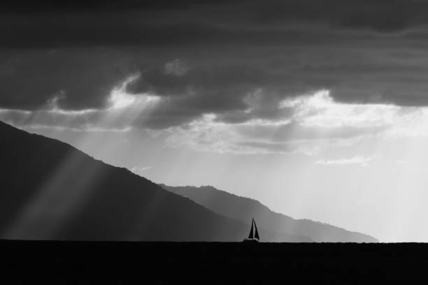Pozzallo, Sicily 31st December 2019. Large transport ships plying to and from Sicily in the early morning, lit by shafts of sunlight breaking through storm clouds.