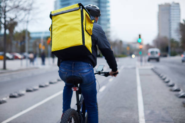 a young delivery rider in a bike. - bicycle messenger imagens e fotografias de stock