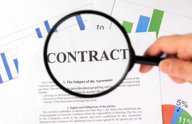 istock Businessman holding magnifying glass zoom and analyzing contract on chart background. 1318997974
