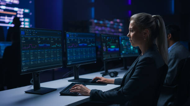 istock Confident Female Data Scientist Works on Personal Computer in Big Infrastructure Control Room. Team of Stock Market Specialist Use Computers Showing Global Map, Graphs, Charts, Information 1319010453