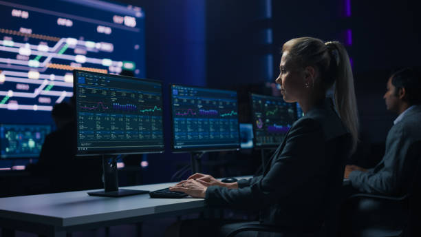 istock Confident Female Data Scientist Works on Personal Computer in Big Infrastructure Control Room. Team of Stock Market Specialist Use Computers Showing Global Map, Graphs, Charts, Information 1319010476