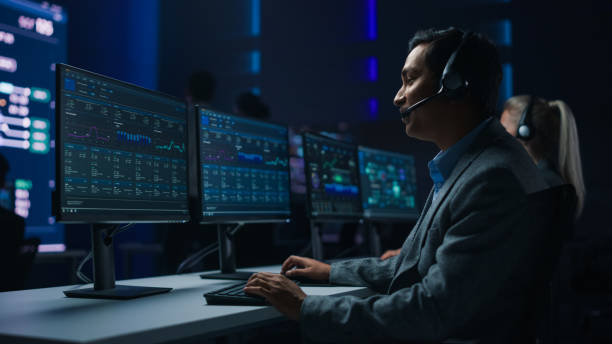 Professional Customer Support Specialist Wearing Headset Talks with Client and Works on Computer in Big Call Center Control Room. Team of Sales Representatives Service Providers Talk with Investors Professional Customer Support Specialist Wearing Headset Talks with Client and Works on Computer in Big Call Center Control Room. Team of Sales Representatives Service Providers Talk with Investors dispatcher stock pictures, royalty-free photos & images