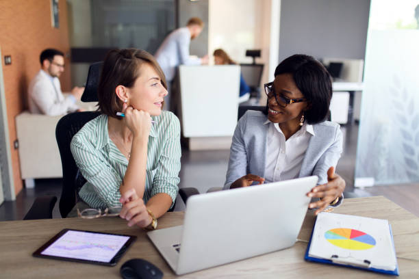 istock Businesswomen with laptop, digital tablet and chart papers cooperating 1319010560