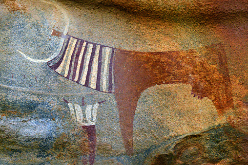 Laas Geel, Maroodi Jeex region, Somaliland, Somalia: domesticated auroch cow draped in ceremonial robes and an open arms stylized human figure - vestiges of a pastoral culture, cave paintings located in a red granite outcrop near the nomadic settlement of Dubato, 55 km from Hargeisa - some of the earliest and best-preserved rock paintings in the Horn of Africa and on the African continent as a whole, suggested dates vary between 4000 BC and 3000 BC.