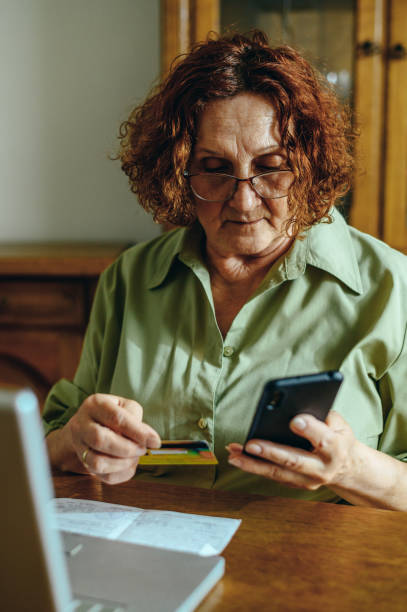 istock Senior woman using a smartphone and a credit card while online shopping 1319014648