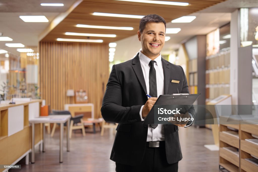 Receptionist in a hotel lobby holding a clipboard Receptionist in a hotel lobby holding a clipboard and looking at camera Hotel Stock Photo