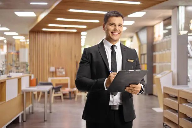 Receptionist in a hotel lobby holding a clipboard and looking at camera