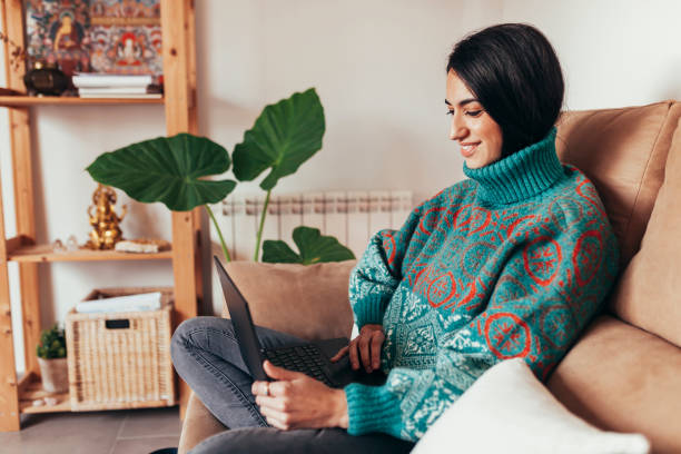 istock Woman sitting on sofa and using laptop 1319019606